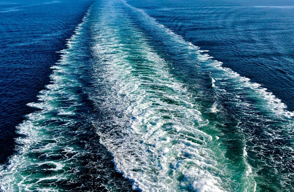 Speedboat wake cutting across blue open sea