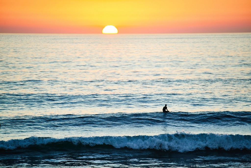 Surfer riding an ocean wave at sunset